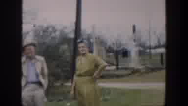 Cuba (1951): Woman Wearing Yellow Dress Stands Near Brown Pole Waving At Camera On
