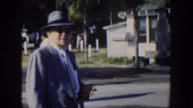 Cuba (1951): Man Wearing Grey Suit Walks Past White Building On A Sunny Day