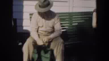 Cuba (1951): Man Wearing Grey Hat Sits On Green Bench On A Sunny Day