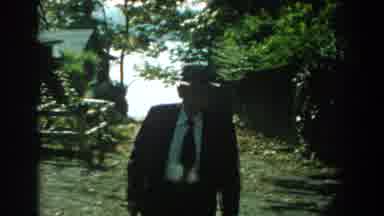 Michigan (1959): Man Wearing Grey Hat Walks Toward Camera On A Sunny Day