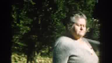 Michigan (1959): An Old Woman In Ash Colored Jacked Walking Around In The Yard