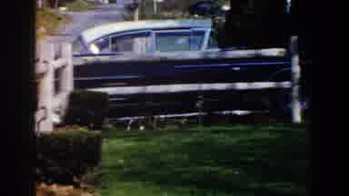 Michigan (1959): View Of Blue Car Parked Near White Wooden Fence On A Sunny Day