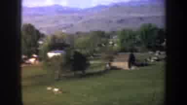 Oregon (1957): A Vehicle Passes Through A Valley Filled With Trees And Homes At