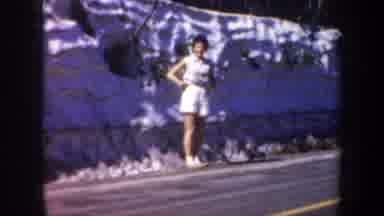Oregon (1957): Woman Wearing White Shorts Stands On Side Of Road On A Bright Sunny