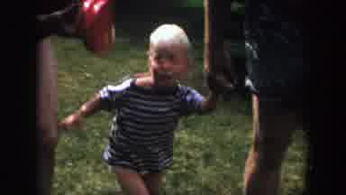 Wisconsin (1958): Woman Wearing Grey Dress Holds Hand Of Toddler Wearing Blue And