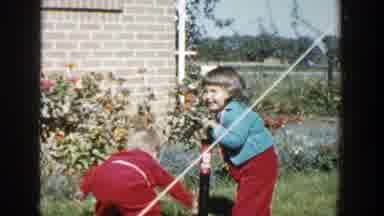 Wisconsin (1958): Two Small Kids Playing With An Air Pump In The Grass While Their