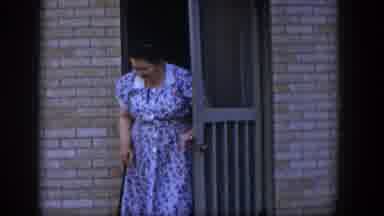 Las Vegas Nevada (1954): Woman Wearing Blue Dress Walks Out Of Tan Screen Door On