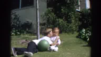North Hollywood California (1964): Boy Wearing White Shirt Kisses Baby Sitting On