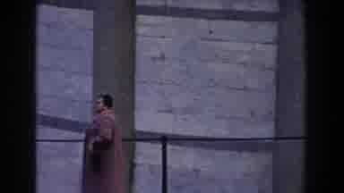 Pisa Italy (1959): Woman Wearing Pink Coat Walks Past Tan Columns On A Clear Day