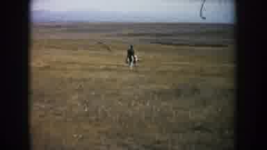 South Dakota (1953): Man Rides A Black And White Horse Through A Spare Countryside