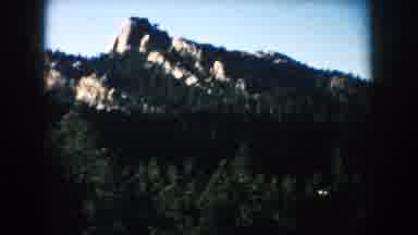 South Dakota (1953): View Of Light Grey Rocks And Green Trees On A Clear Sunny Day