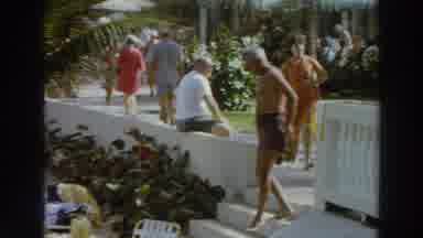 PUERTO RICO-1966: Man in White Shirt Walks Past Thatched Hut in Tropical Resort