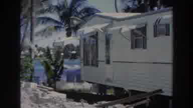 Puerto Rico (1966): Man Wearing Light Blue Shirt Stands Near Tan Mobile Home