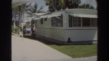 Puerto Rico (1966): Man Wearing Grey Shirt Walks Alongside White And Green Mobile