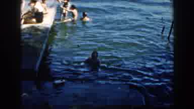 Brighton Michigan (1960): Children Play In The Water Next To A Dock While A Woman