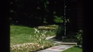 Brighton Michigan (1960): View Of Brown Building With White Blooming Flowers On A