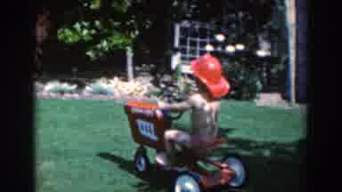 North Hollywood California (1961): Baby In Swimsuit Plays With A Toy Tractor On A
