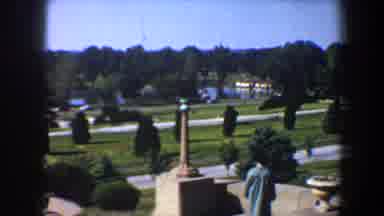 Saint Louis Missouri (1964): A Man Wearing A Trench Coat And Hat Walks By A Statue