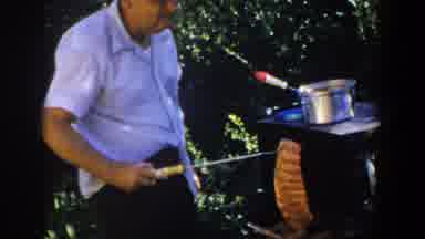 Lubbock Texas (1953): Man Uses Cooking Utensil To Pick Up Meat From Grill To Look