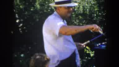 Lubbock Texas (1953): Man Wearing White Shirt Checks Food On Barbecue Grill On A