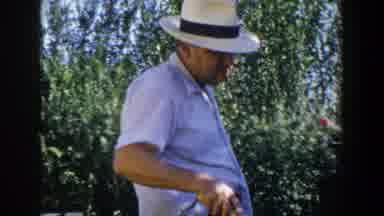 Lubbock Texas (1953): Old Man Wearing Hat Cooks Food On A Grill Outside