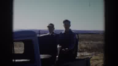 Lubbock Texas (1957): A Man And His Friend Sit Behind A Truck And Eat