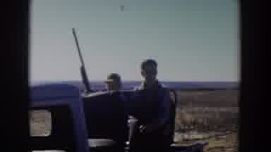 Lubbock Texas (1957): Two People Sitting In Back Of White Truck On A Sunny Day