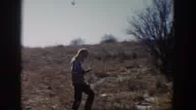 Lubbock Texas (1957): Man Wearing Tan Hat Walks Through Field Carrying Rifle On A