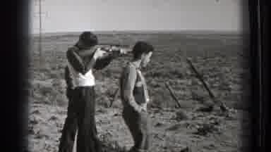 Washington (1939): Man Wearing Black Pants Aims Rifle While Man Wearing Grey Hat