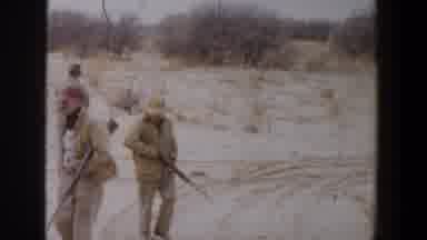 Lubbock Texas-1956: Three Hunters Walk Through Sandy Terrain With Rifles