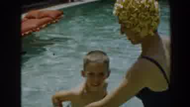 North Hollywood California (1961): Woman Wearing Blue Swimwear Helps Boy Swim In