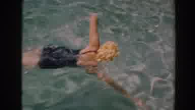 North Hollywood California (1961): Woman Wearing Yellow Swim Cap Swims Towards Man