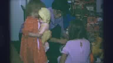 Blue Springs Missouri-1973: Woman in Purple Shirt Picks Up Yellow Gift Box at Christmas