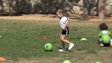LOS CABOS MEXICO-2019: A Happy Little Girl Running And Kicking A Ball Towards