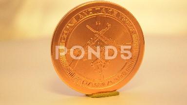 A Bright Shining Gold Coin Placed On A Holder Is Making Slow Rotations