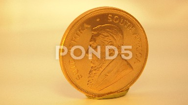 A Golden Coin With A Face On One Side And It Is Spinning Around