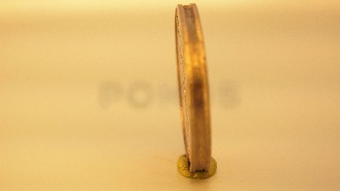 A Yellow $ Coin Held Upright By A Modeling Clay Base Rotates While On Display