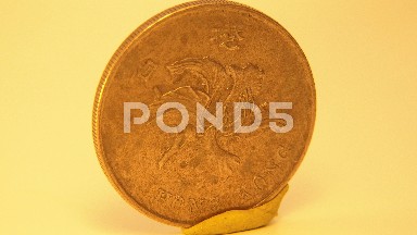 Gold Coin Slowly Orates On Yellow Putty And Maize Colored Background