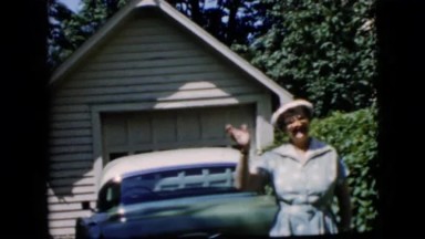 1969: California. A Woman Standing In Front Of A Green Car.