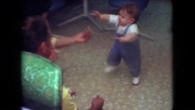 1966: Athens Ohio, USA. A Small Child Standing Next To A Man On A Couch.
