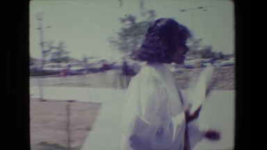 1983: Lansing Michigan. A Black And White Photo Of A Woman Walking Down A