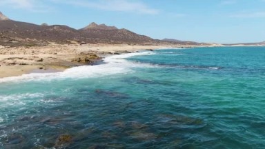 BUZZARDS BEACH EAST CAPE BCS MEXICO-2023: A Calm Body of Water Next to a Sandy Beach