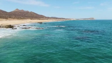BUZZARDS BEACH EAST CAPE BCS MEXICO-2023: A Calm Body of Water Next to a Sandy Beach