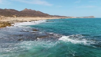 BUZZARDS BEACH EAST CAPE BCS MEXICO-2023: A Calm Body of Water Next to a Sandy Beach