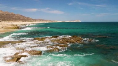 BUZZARDS BEACH EAST CAPE BCS MEXICO-2023: A Calm Body of Water Next to a Rocky Shore