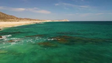 BUZZARDS BEACH EAST CAPE BCS MEXICO-2023: A Body of Water With a Mountain in the Background
