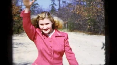 1956: Woman Smiling and Posing for a Picture in Pink Jacket and Golden Halo