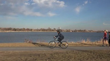 DENVER, COLORADO-2015: Bike Rider in Front of Scenic Lake