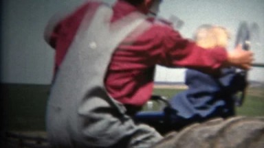 (8mm Vintage) 1952 Man Smoking Pipe Driving Tractor With Child On Lap. Iowa,