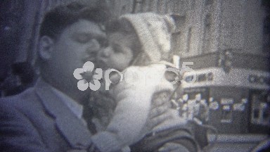 1946: Dad kissing baby in the busy urban streets of downtown New York City.